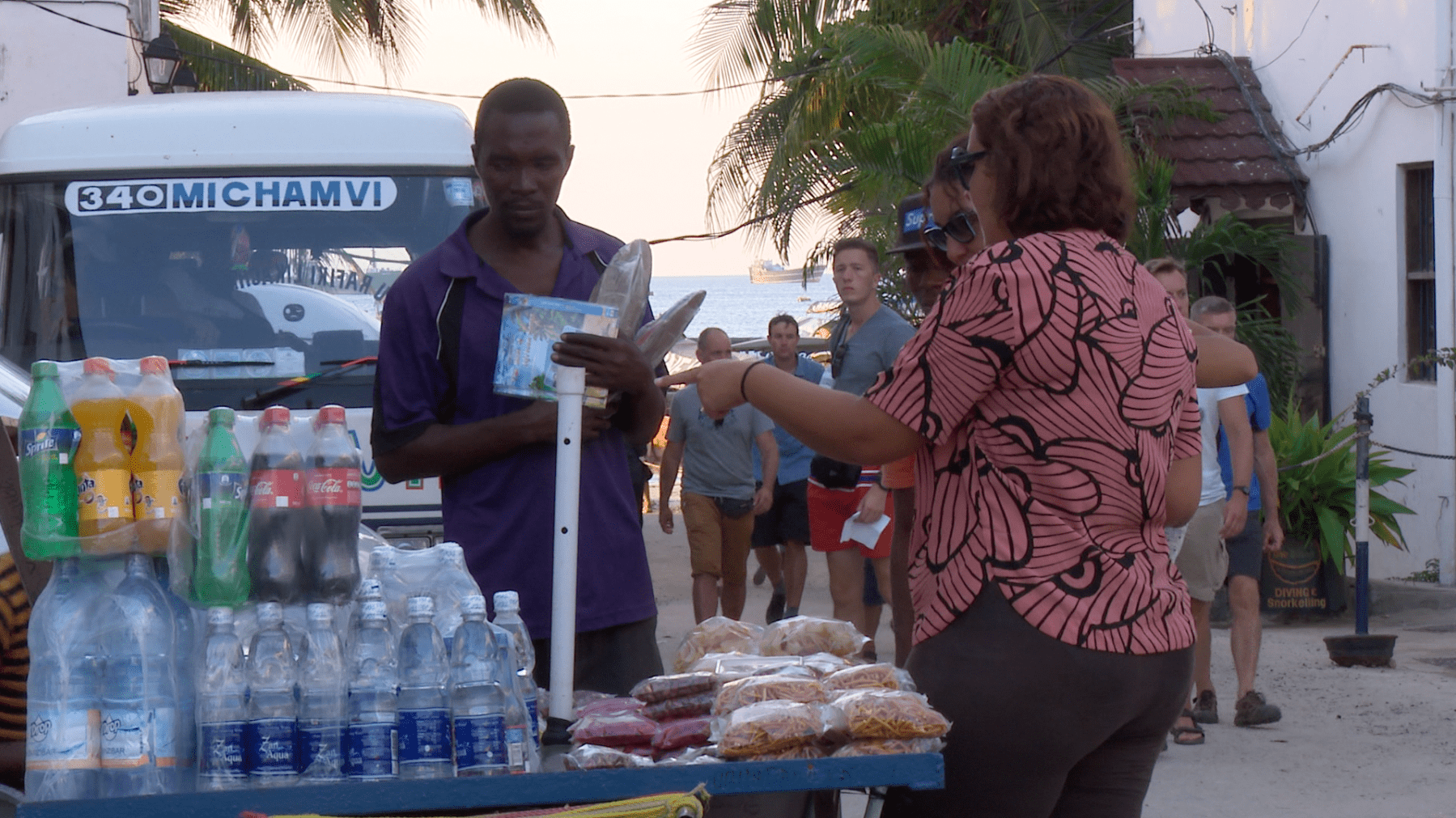 Street vendor selling plastic bottles to a tourist