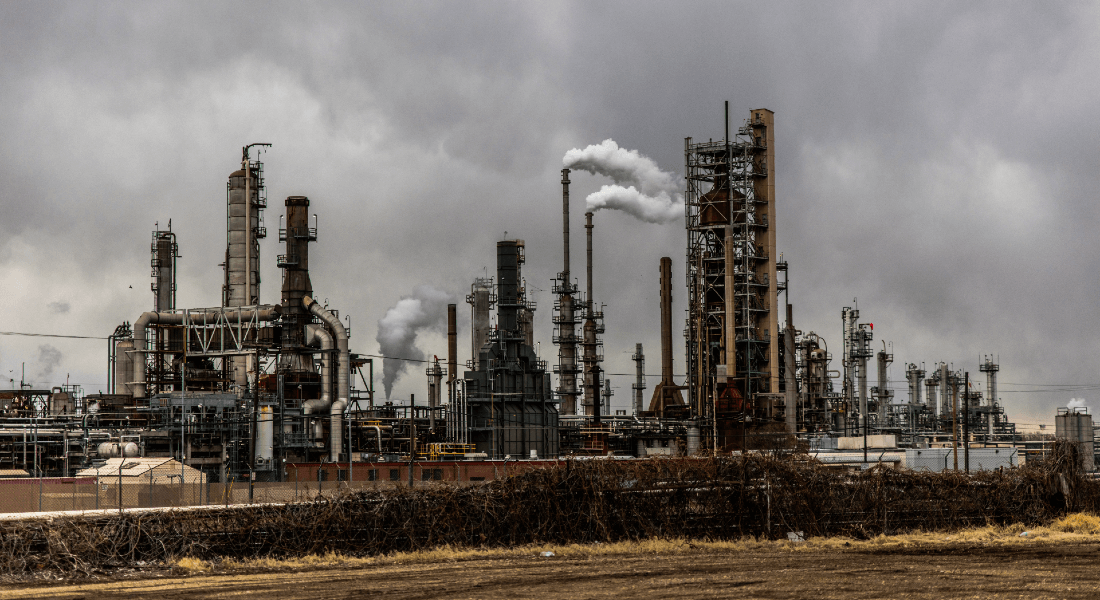 Factory with smoke under cloudy sky